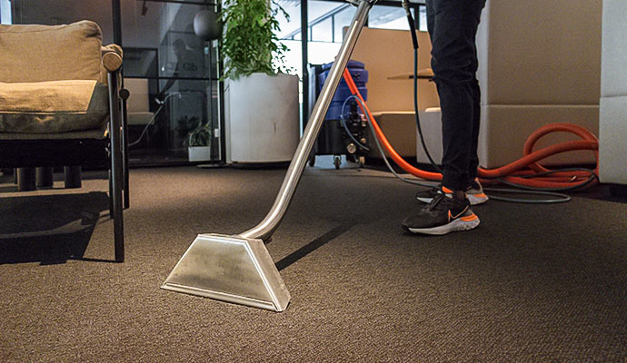 Professional commercial carpet cleaning with steam extraction wand in an office