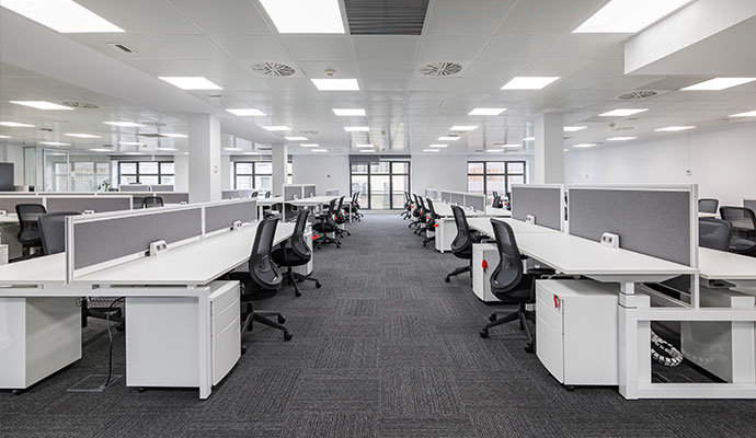 Spacious modern open-plan office building with clean workstations and carpet flooring