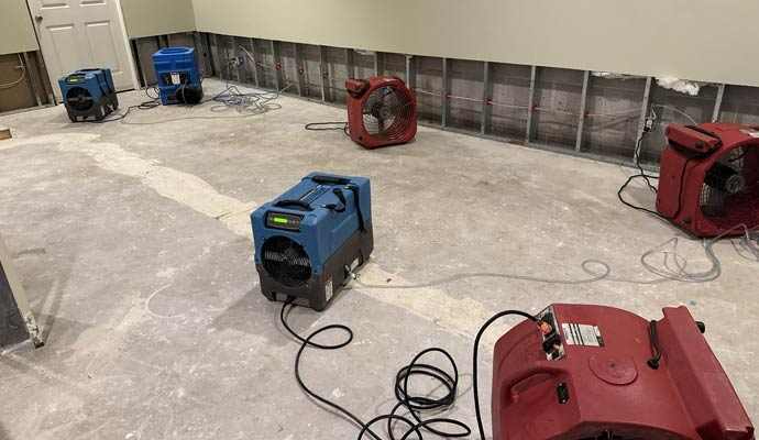 Dehumidifiers and air movers drying a water-damaged room.