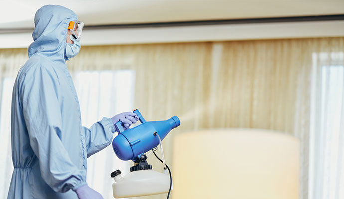 Professional disinfecting a room with a fogging machine