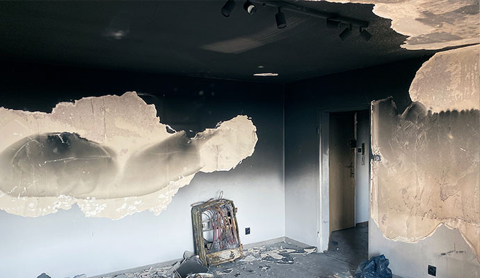 Fire damaged interior room with soot blackened ceiling and damaged drywall