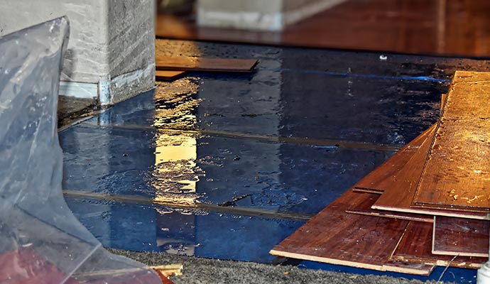 Flooded hardwood flooring with standing water and damaged floor panels inside