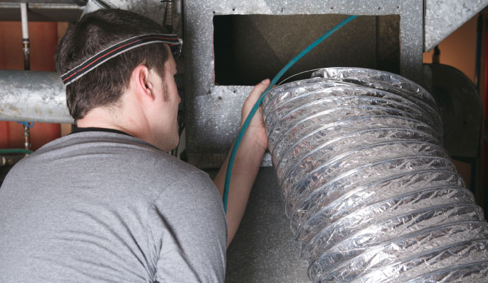 Technician cleaning HVAC ductwork to remove smoke residue and odors