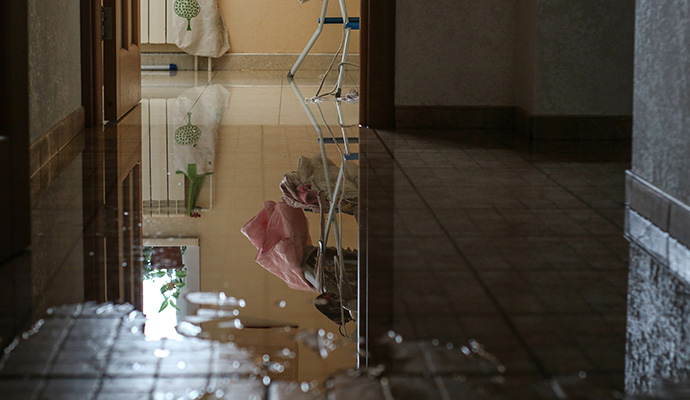 Flooded residential hallway with standing water on tiled floor from plumbing leak