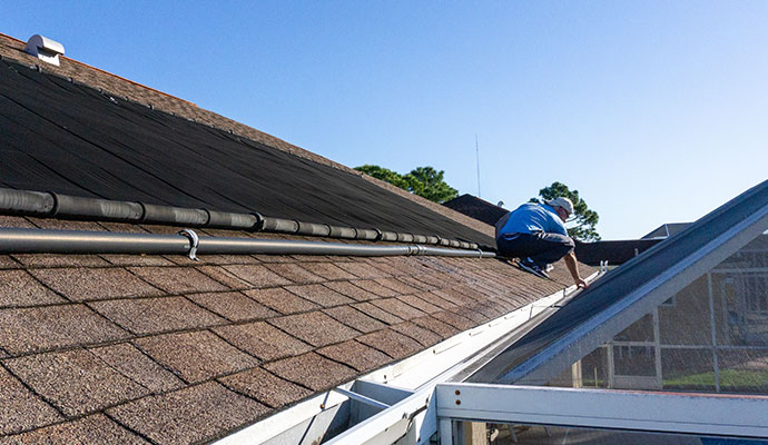 A person is cleaning gutter of roof