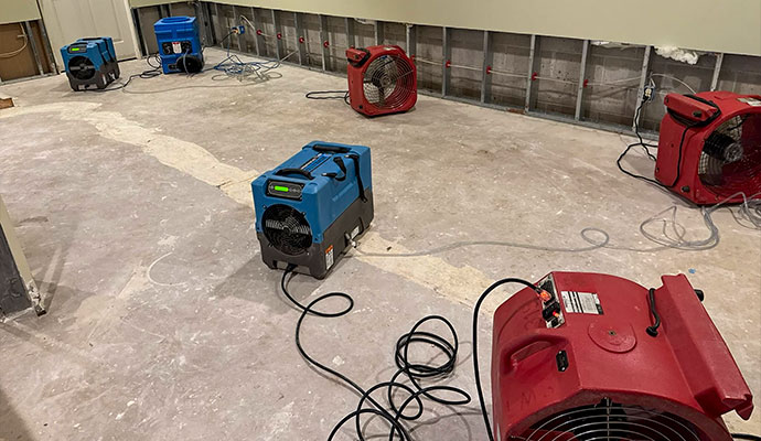 Industrial dehumidifiers and air movers drying water damaged room