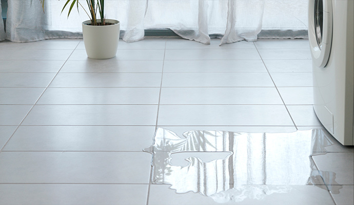 Water leaking from washing machine onto tiled laundry room floor
