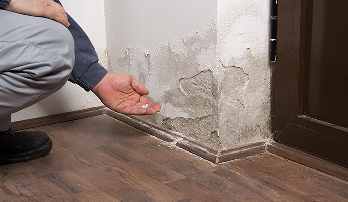 A person is inspecting structurally damaged wall